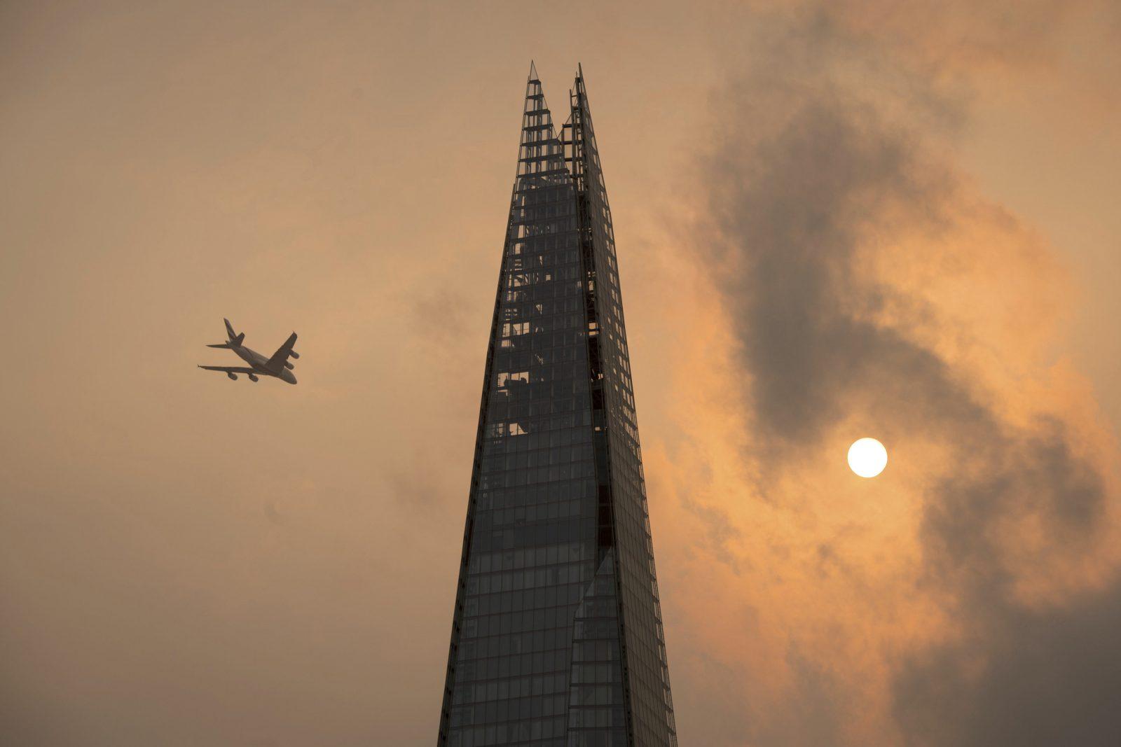 A plane flies past the Shard in central London, as the sky takes on an unusual orange colour caused by Hurricane Ophelia Monday Oct. 16, 2017. The unusual occurrence was due to the remnants of the hurricane dragging in tropical air and dust from the Sahara.  (Dominic Lipinski/PA via AP)